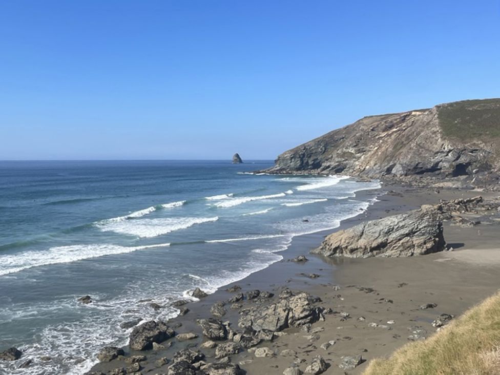 A beach with waves and cliffs at Copper Mine Cottage in Trelill near Port Isaac