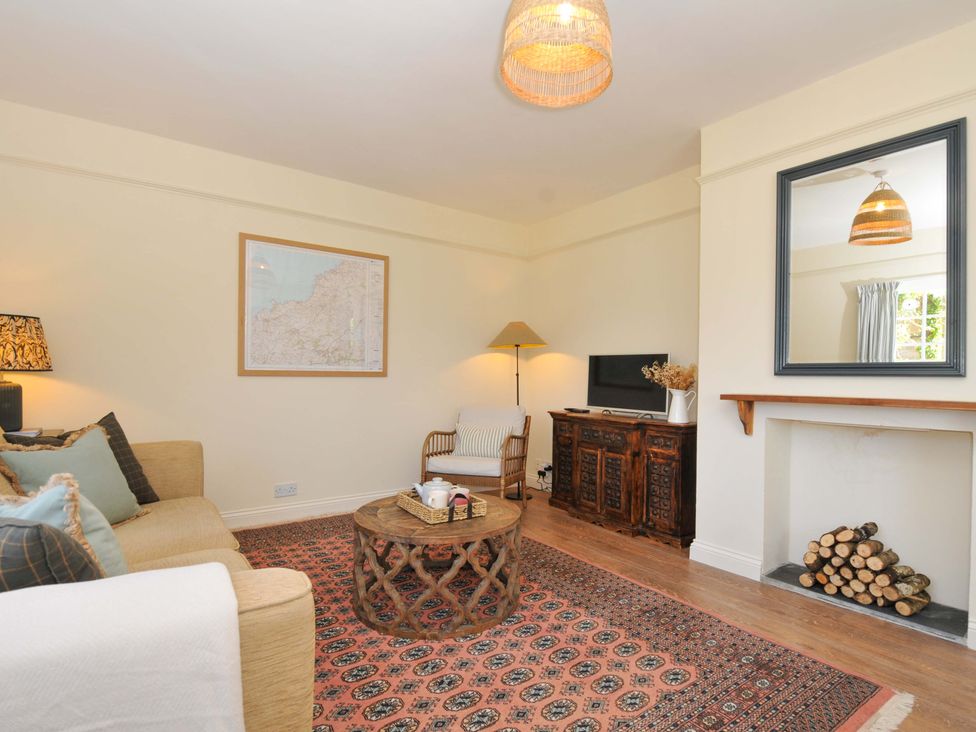 A living room with a sofa, table and TV at Copper Mine Cottage in Trelill near Port Isaac