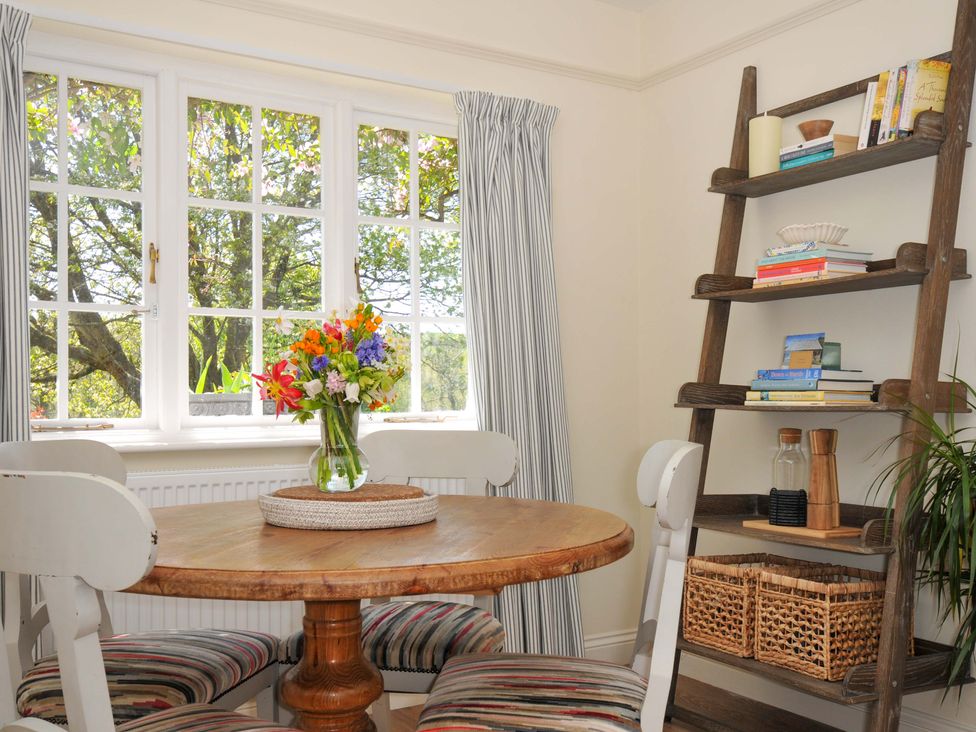 A dining room with a table, chairs and flowers at Copper Mine Cottage, Trelill near Port Isaac