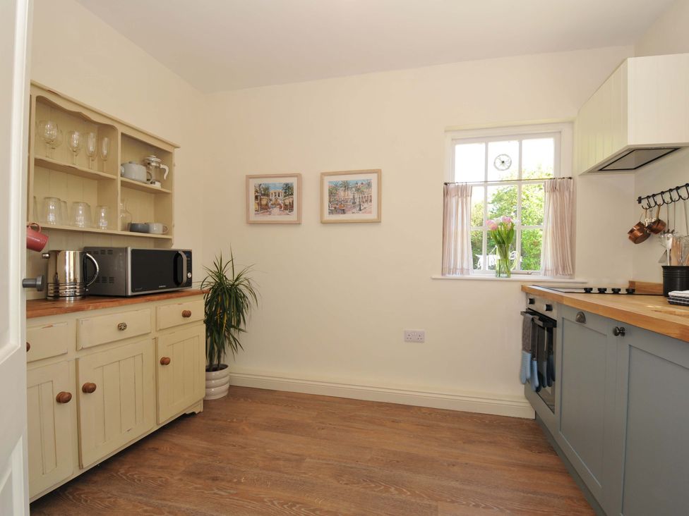 A kitchen with cabinets and a microwave at Copper Mine Cottage, Trelill near Port Isaac