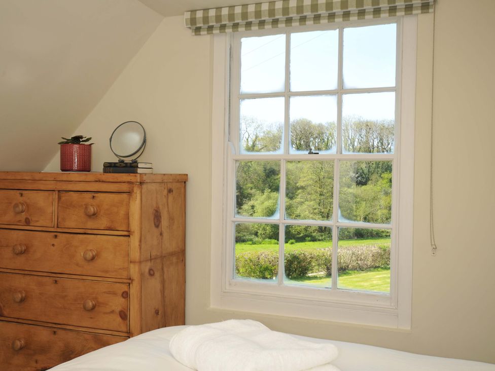 A bedroom with a window and a chest of drawers at Copper Mine Cottage Trelill near Port Isaac
