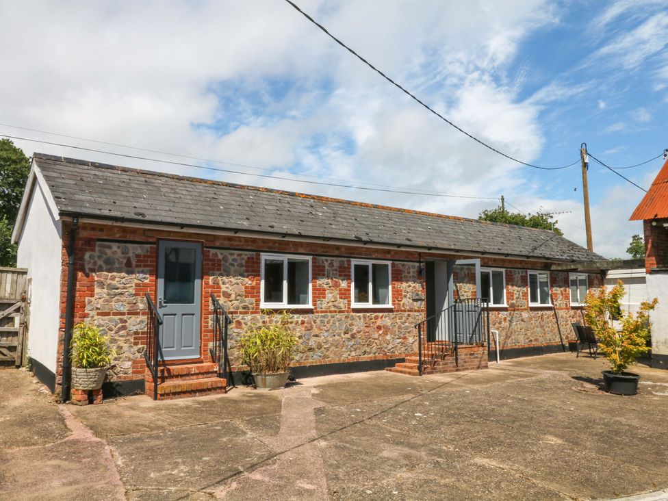 An outdoor view of a stone building with a blue door and windows at The Milk Shed in Plymtree
