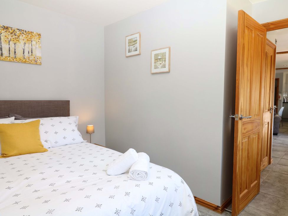 A bedroom with a bed, lamp, and artwork at The Milk Shed in Plymtree