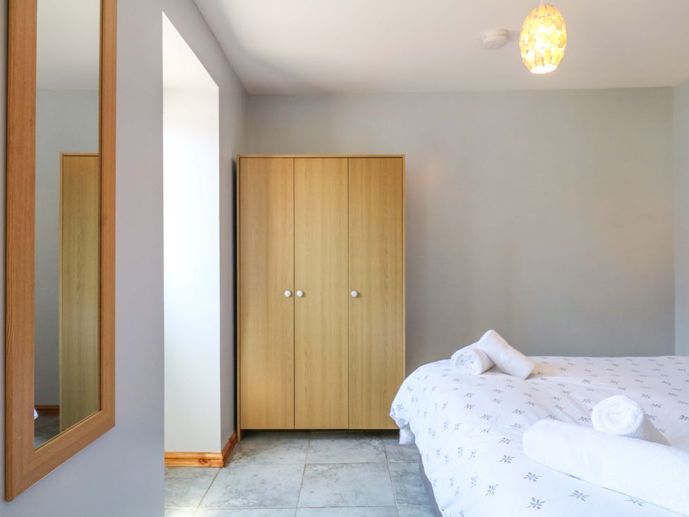 A bedroom with a mirror and wardrobe at The Milk Shed Plymtree
