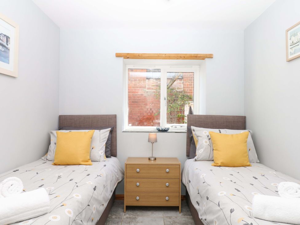 A bedroom with two beds and a nightstand at The Milk Shed in Plymtree