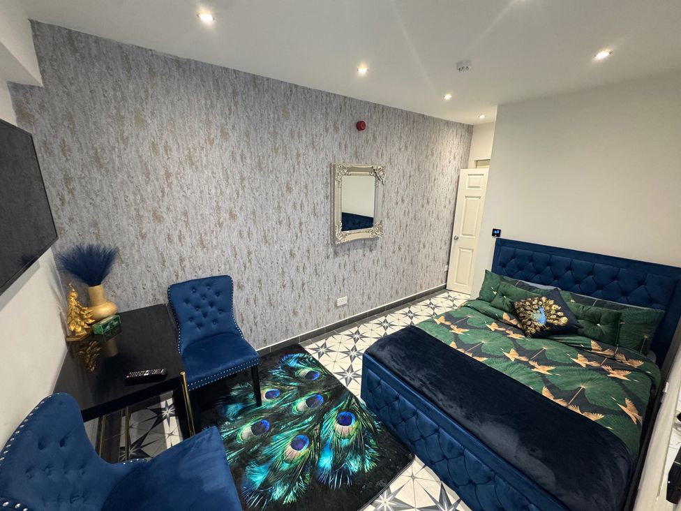 A bedroom with a bed, chairs, and a mirror in an apartment