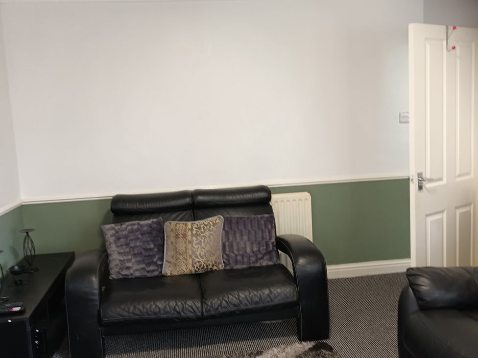 A living room with a sofa and cushions at 11 Kings Court