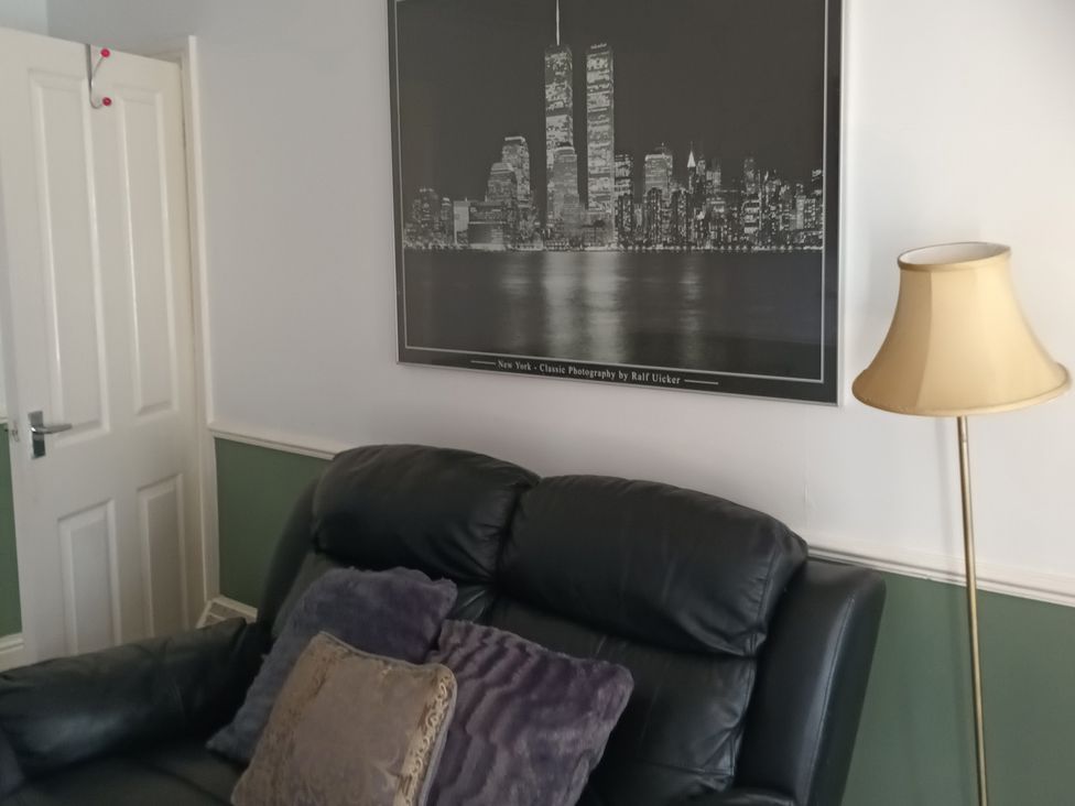 A living room with a leather sofa and a wall-mounted picture at 11 Kings Court 