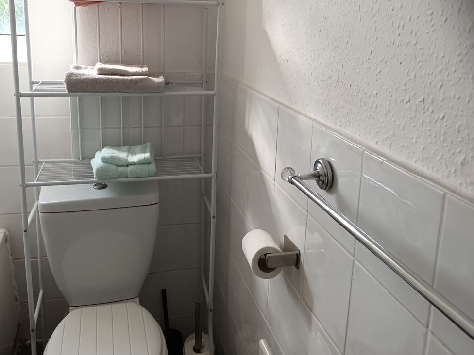 A bathroom with a toilet and shelf holding towels at 11 Kings Court
