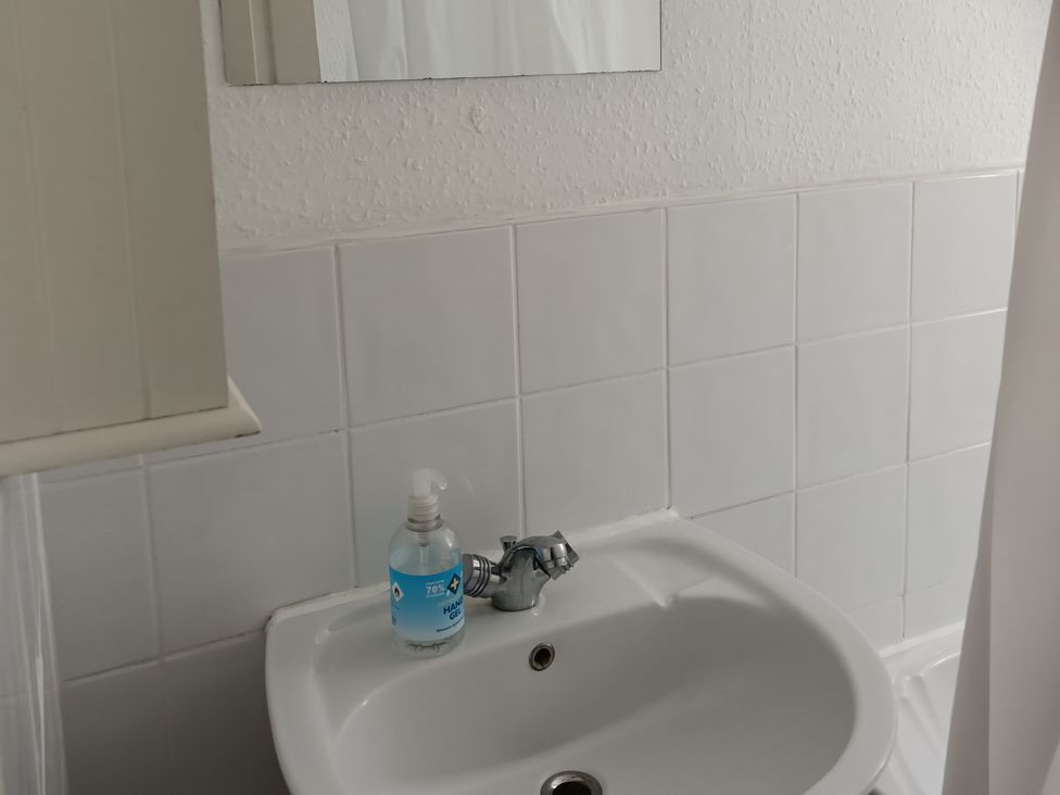 A bathroom with a sink and soap dispenser at 11 Kings Court