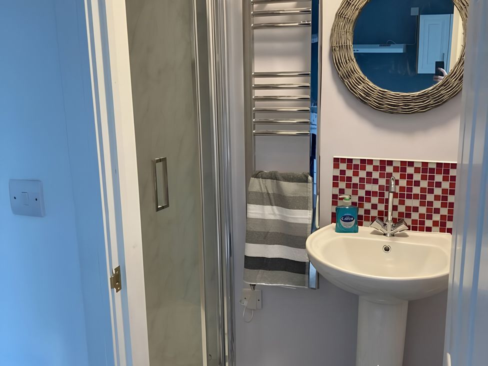 A bathroom with a sink, shower, towel rack, and mirror at The Nook 