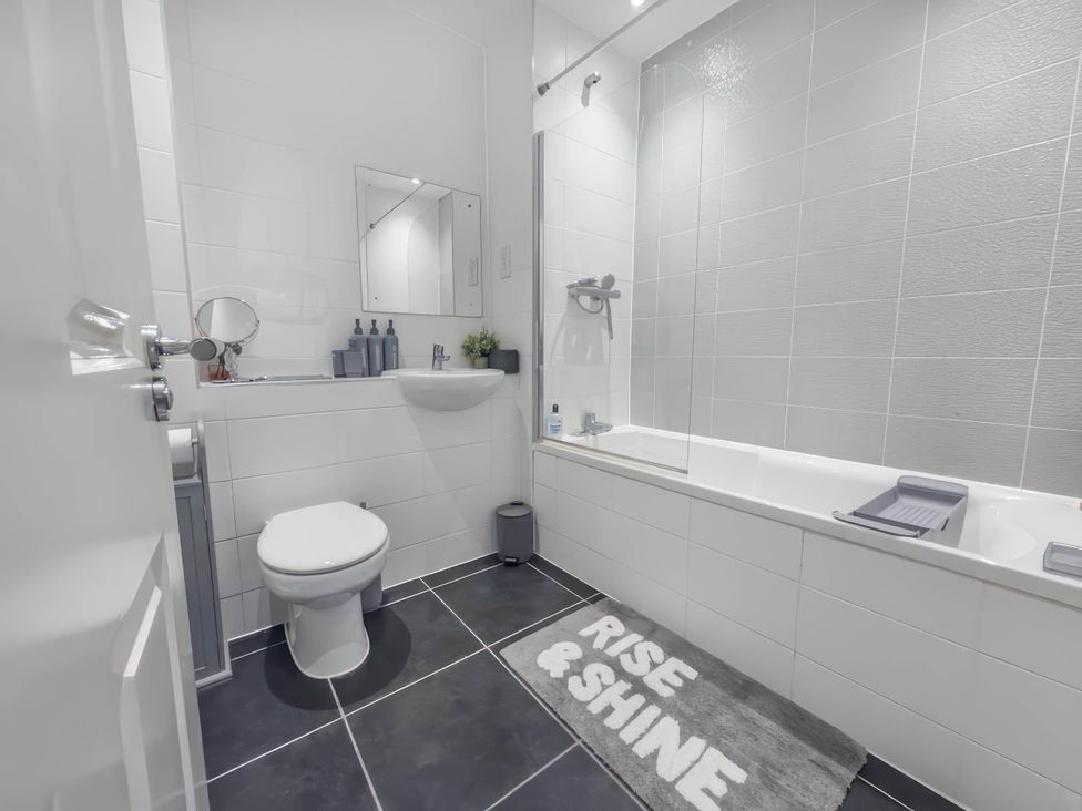 A bathroom featuring a toilet, wash basin, mirror, and bathtub at 