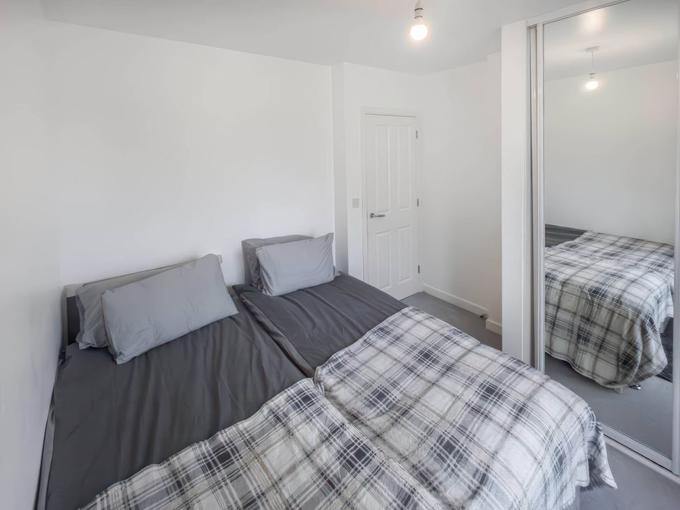 A bedroom with two beds and a mirrored wardrobe