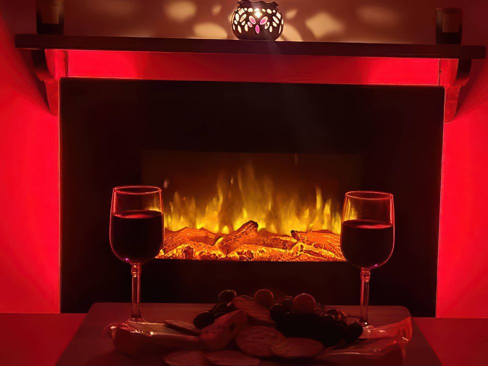 A living room with a fireplace and wine glasses on a table at The Old Barn in Manchester