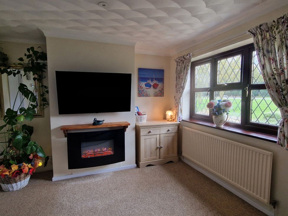 A living room with a television and electric fireplace at Quackers in Heacham