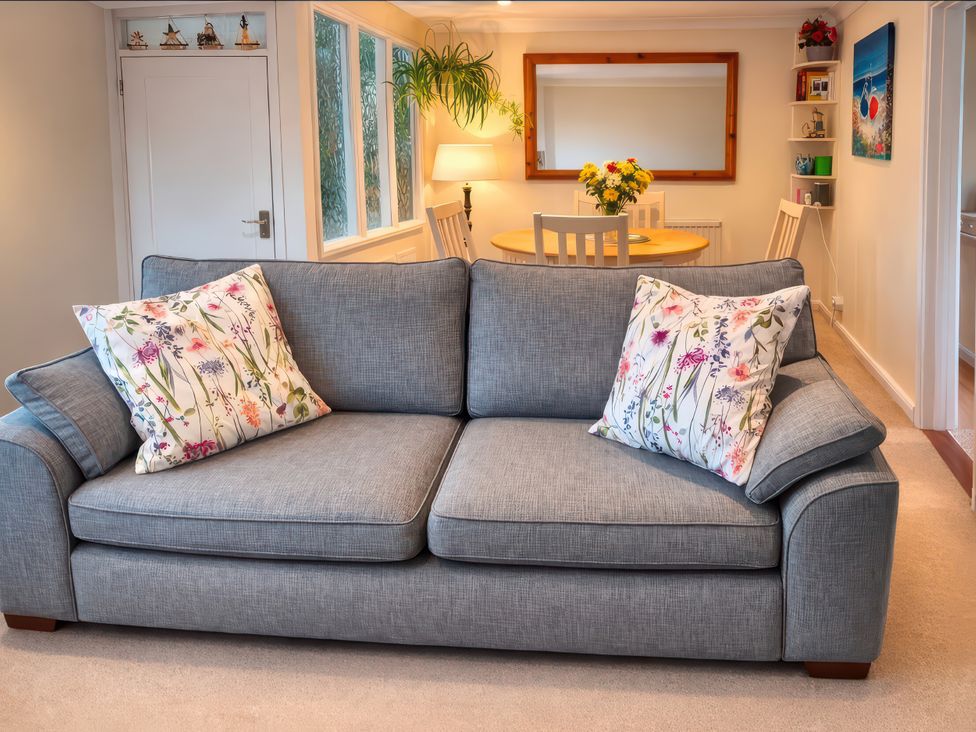 A living room with a sofa and dining table at Quackers Heacham