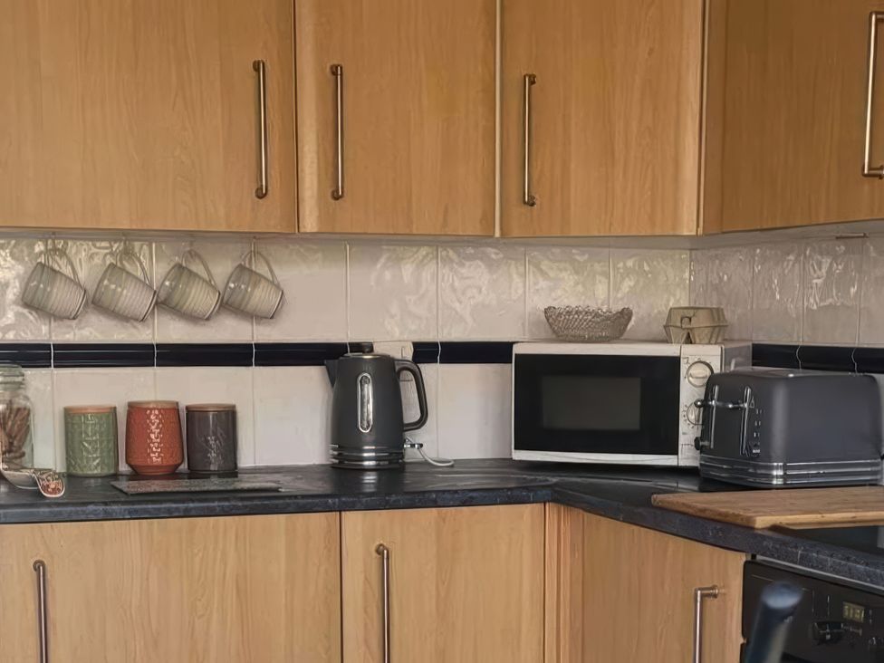 A kitchen with a kettle, toaster, and microwave at Quackers in Heacham