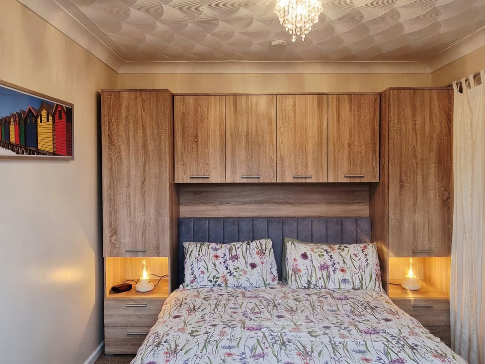 A bedroom with a bed and nightstands at Quackers in Heacham