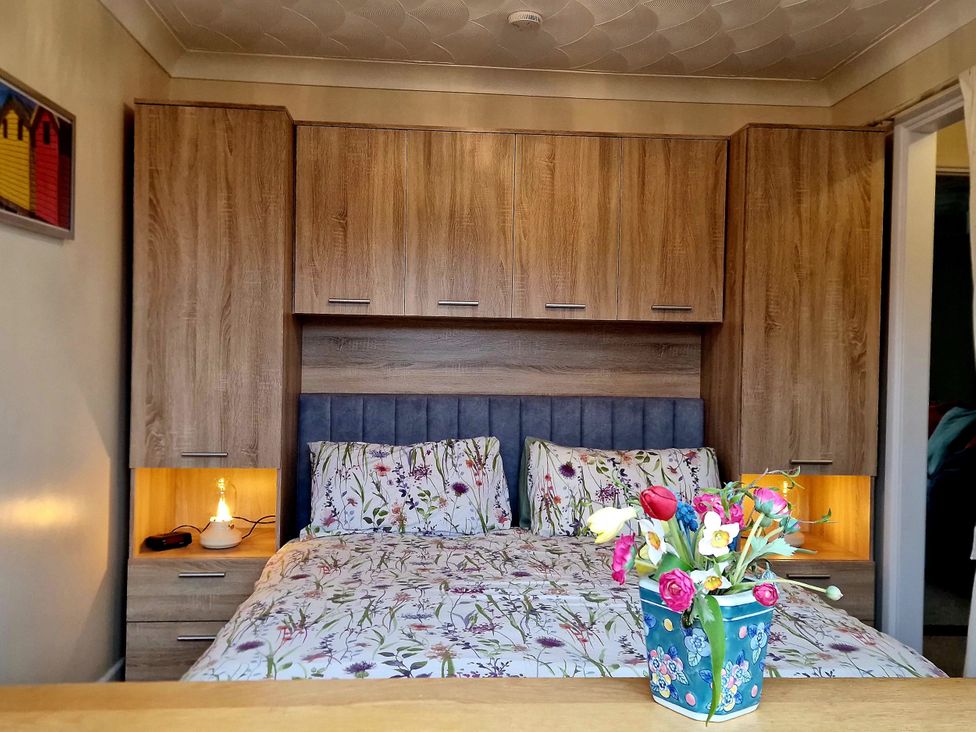 A bedroom with a bed and flower arrangement at Quackers in Heacham