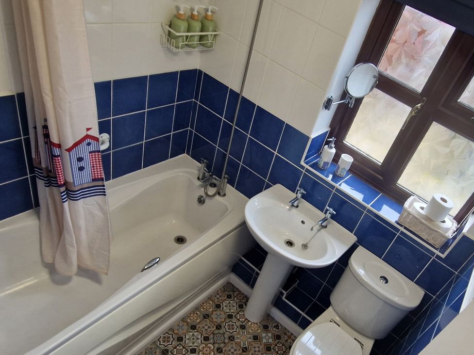 A bathroom with a bathtub, sink, and toilet at Quackers in Heacham