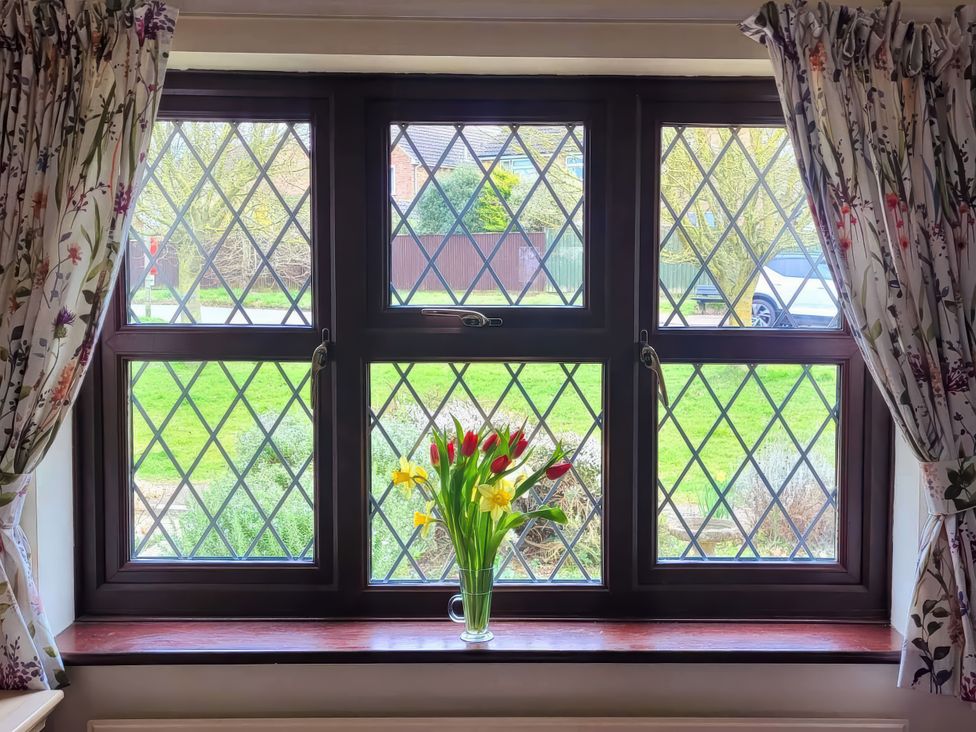 A window with flowers and a view of the garden at Quackers in Heacham