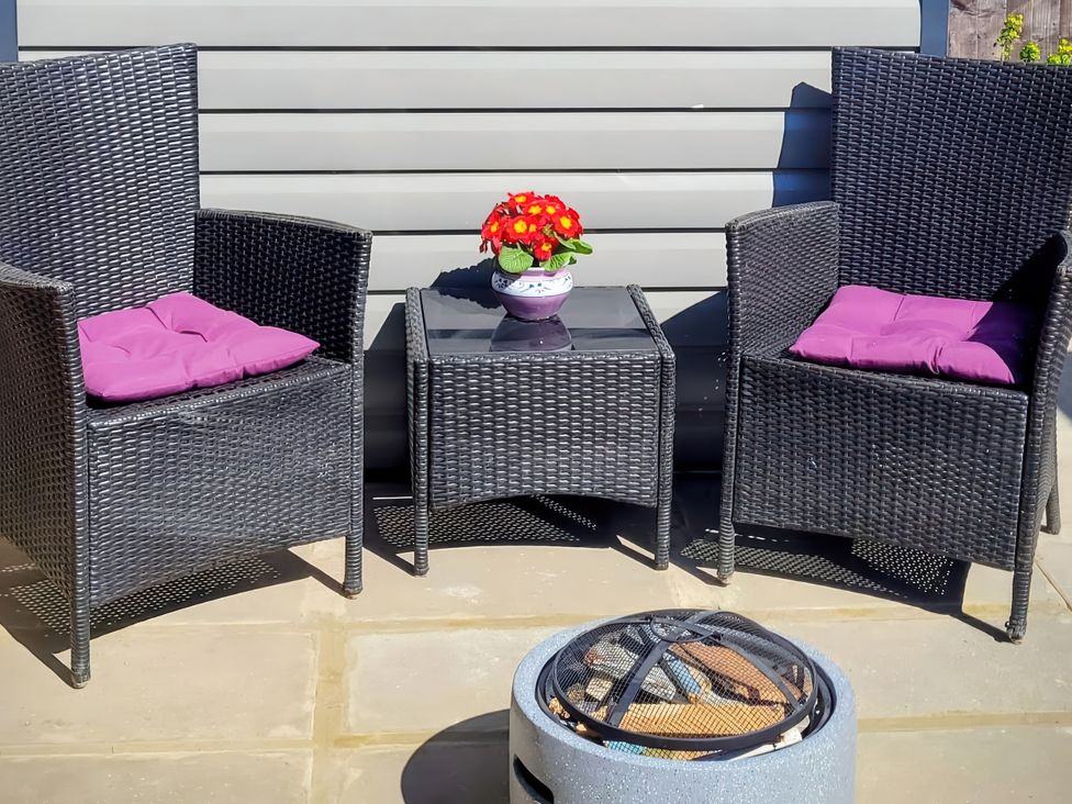 Outdoor seating area with two chairs, a table, and a fire pit at Quackers in Heacham