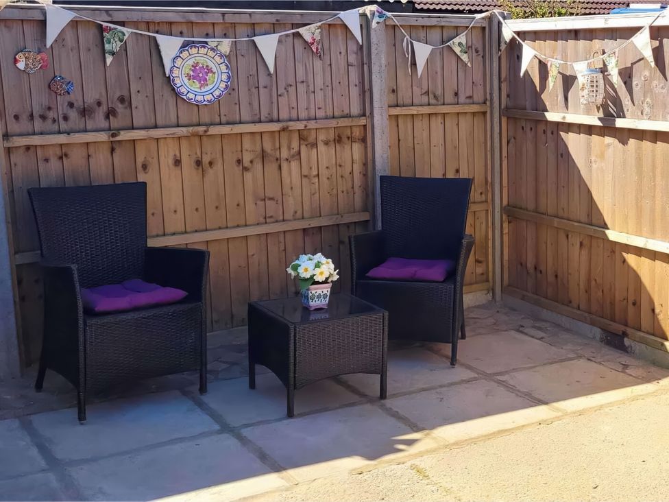 A garden seating area with chairs and a table at Quackers in Heacham