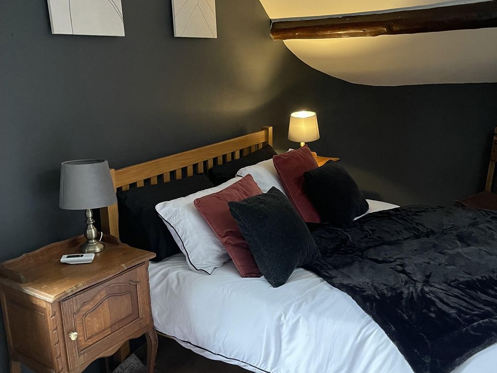 A bedroom with a wooden bed and pillows at High Dyke Cottage