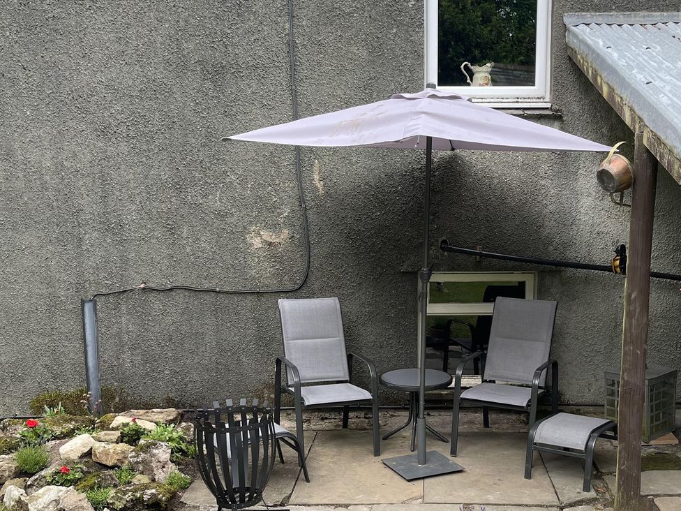An outdoor seating area with chairs and an umbrella at High Dyke Cottage