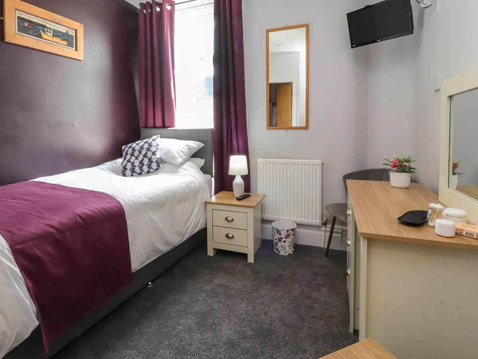 A bedroom with a single bed and a desk at the property in the location