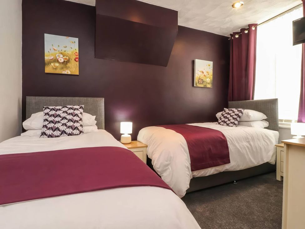 A bedroom with two beds, a lamp, and paintings at 