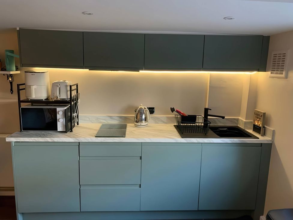 A kitchen with microwave and kettle on the countertop at  