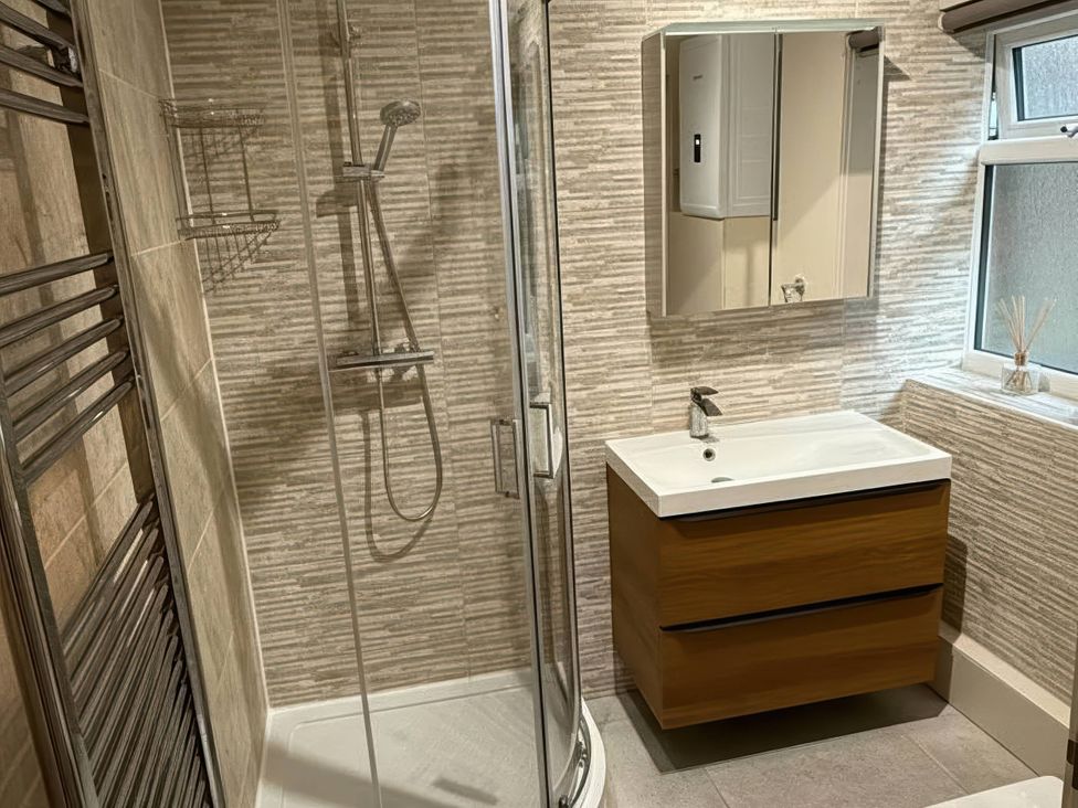 A bathroom with a shower, sink, and mirror at The Old Barn in Manchester