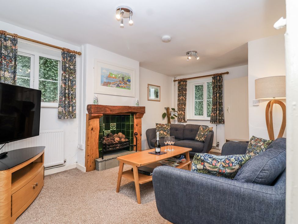 A living room with a fireplace and TV at Orchard Cottage in Dawlish