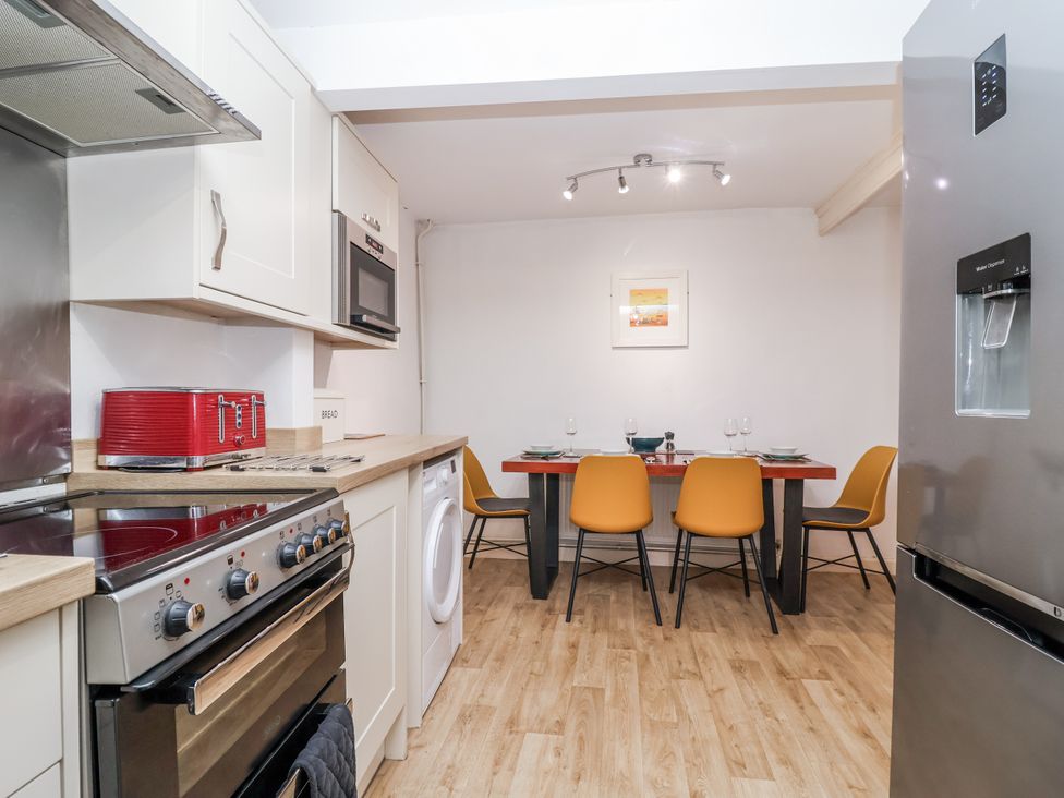 A kitchen with a dining area featuring a table and chairs at Orchard Cottage in Dawlish