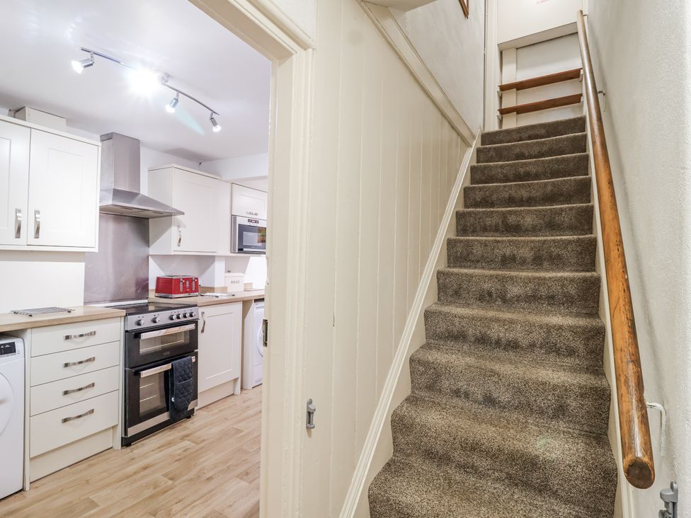 A kitchen with appliances and a staircase at Orchard Cottage in Dawlish