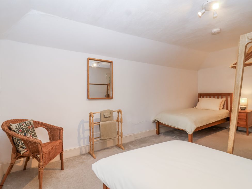 A bedroom with a bed and a chair at Orchard Cottage in Dawlish