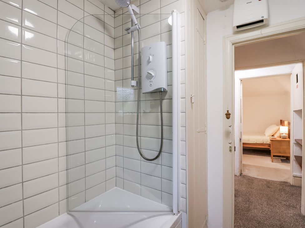 A bathroom with a shower and water heater at Orchard Cottage in Dawlish