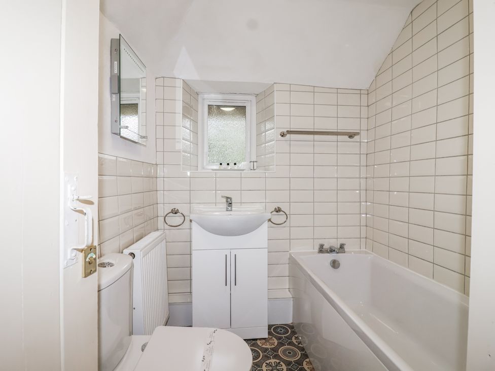 A bathroom with a bathtub and sink at Orchard Cottage in Dawlish