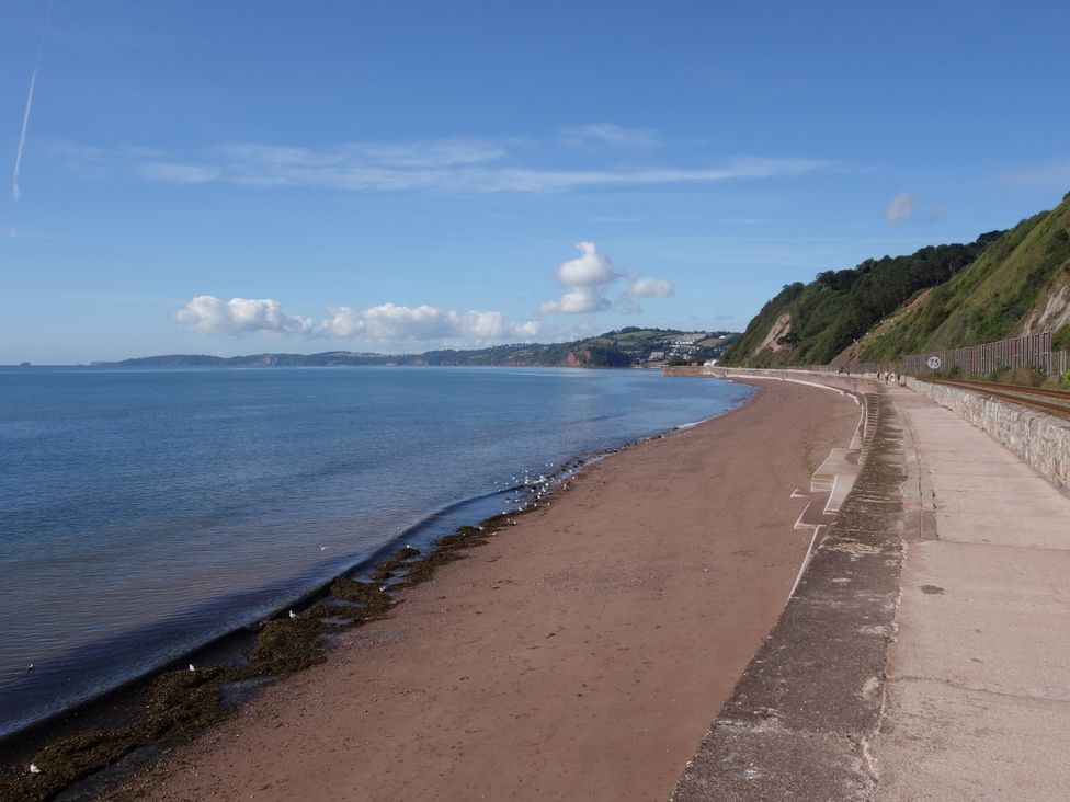 A beach with a path along the water at Orchard Cottage in Holcombe