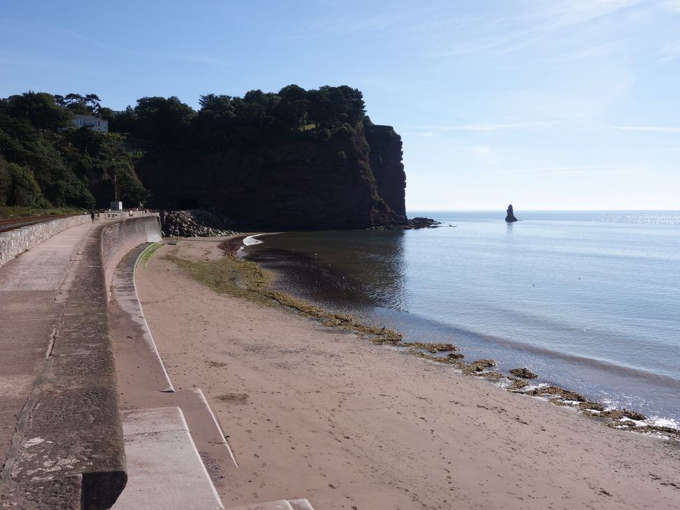A beach with cliffs and a rock formation at Orchard Cottage Holcombe
