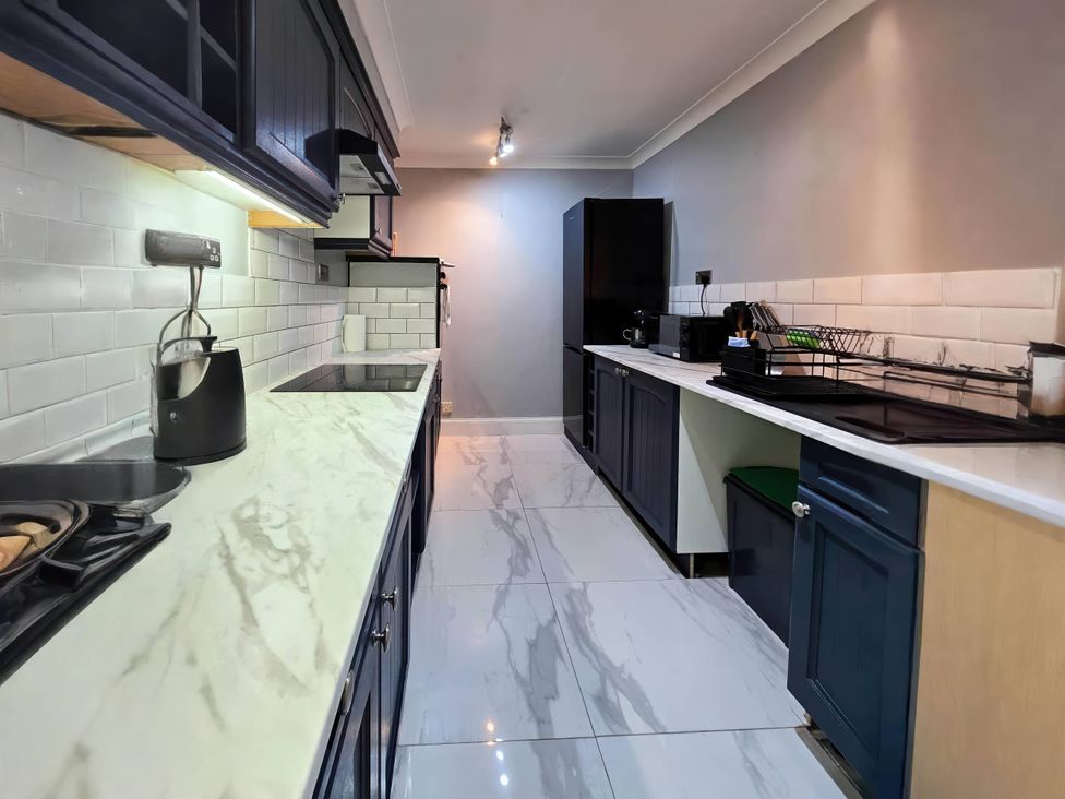 A kitchen with cabinets, countertop, stove, sink, and refrigerator