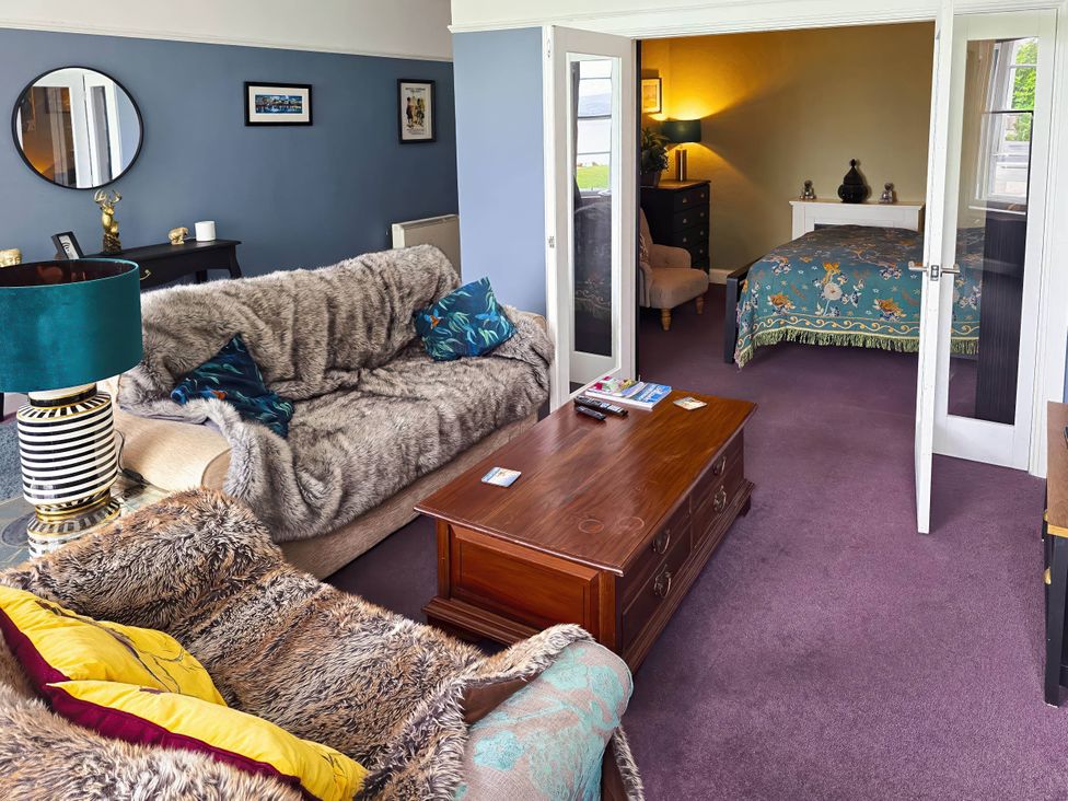 A living room with a sofa and a table leading to a bedroom at the property location