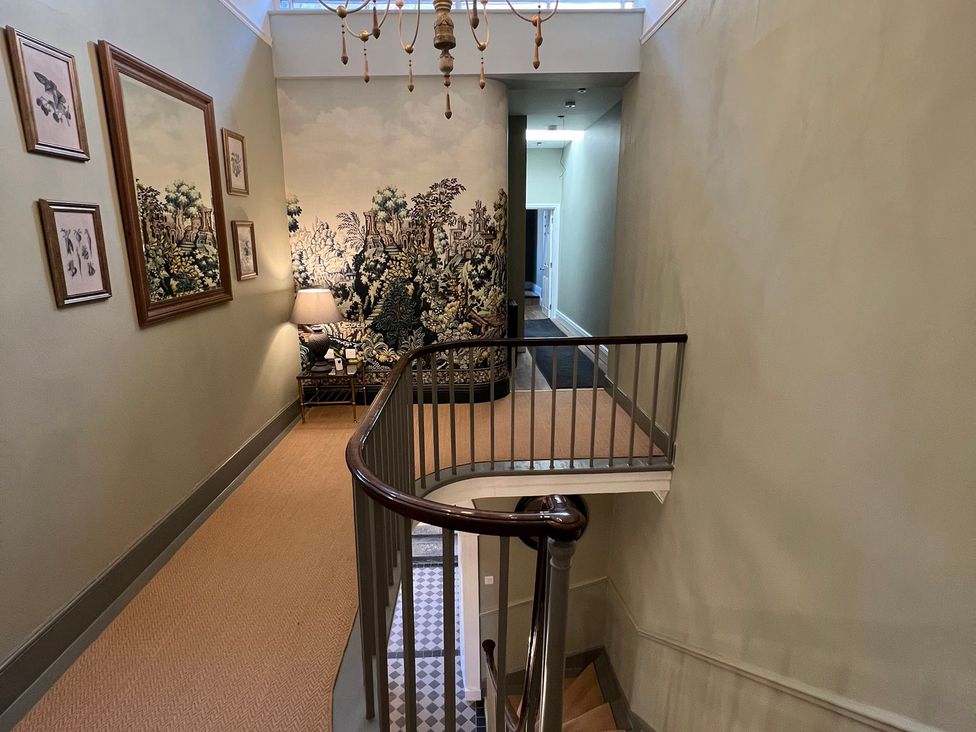 A staircase in a hallway with a mural and framed artwork at ASH HOUSE in Wincanton