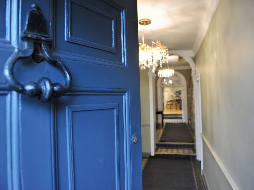 A view of a hallway with chandelier and door at ASH HOUSE in Wincanton