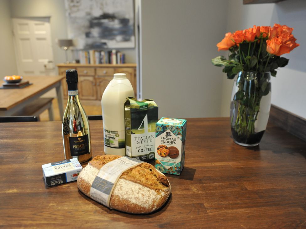 A kitchen table with prosecco, milk, coffee, biscuits, and bread at ASH HOUSE in Wincanton