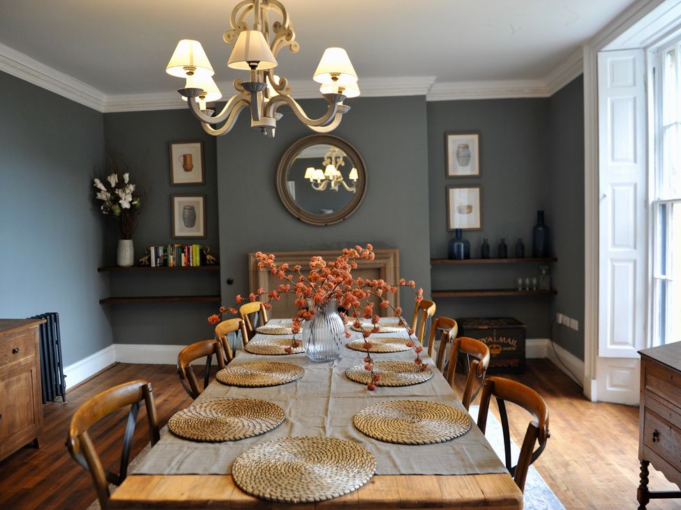 A dining room with a long table and a chandelier at ASH HOUSE in Wincanton