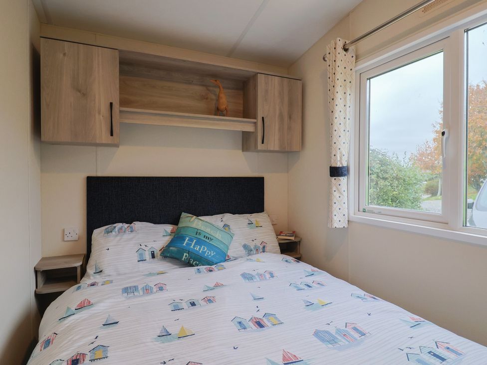A bedroom with a bed and shelves at caravan NEW Uplyme