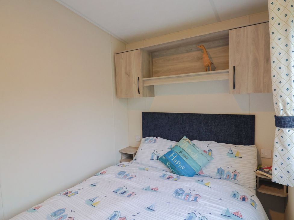 A bedroom with a bed and shelf at caravan NEW Uplyme