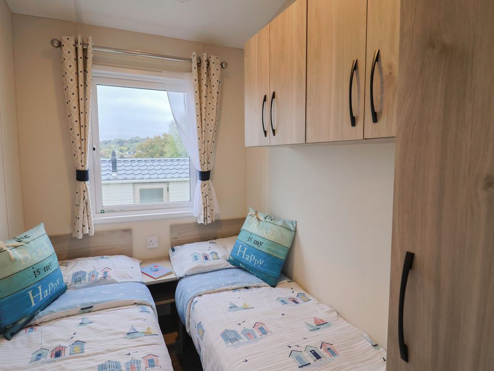 A bedroom with two beds and curtains at caravan NEW in Uplyme